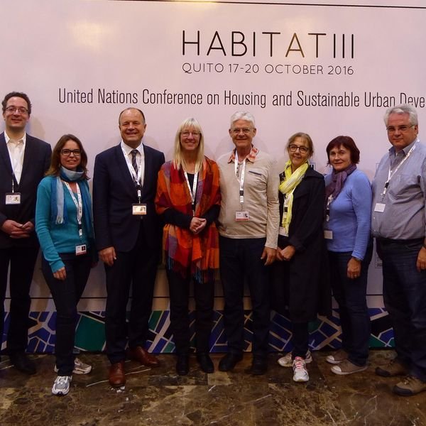 Bild von mehreren Personen vor einem Aufsteller mit der Aufschrift HABITAT III