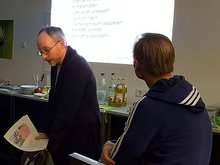Matthias Gastel vor einer Leinwand, auf die ein Beamer die Überschrift "Grundlegende Herausforderungen" und mehrere Unterpunkte projiziert.