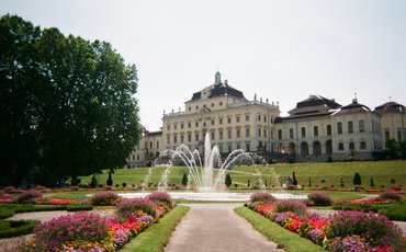 Das Ludwigsburger Schloss durch den Schlosspark hindurch fotografiert, in der Mitte des Bildes ist ein Springbrunnen.