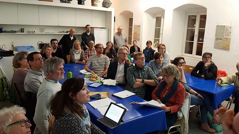 Etwa 25 Menschen sitzen bei der Mitgliederversammlung um zwei Tische.