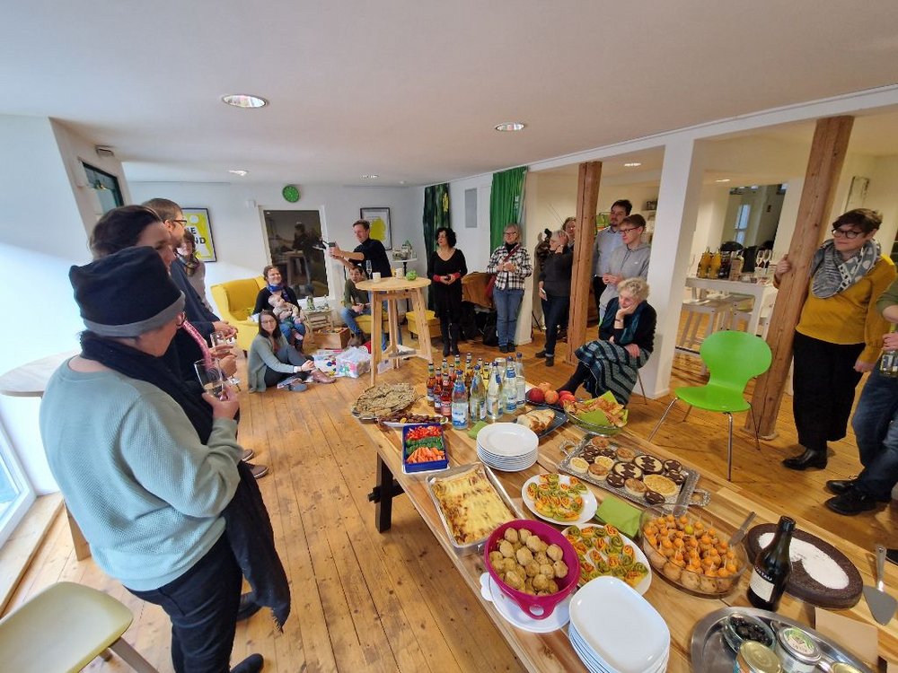 Bild von einem Stehempfang, in der Mitte ist ein Buffet.